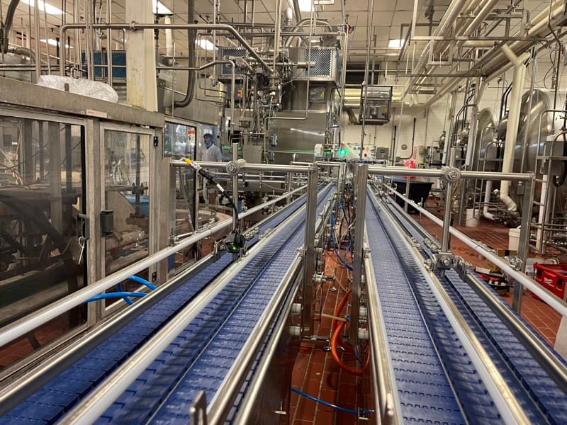 Multi-lane sanitary modular belt conveyors with stainless guide rails merging product in a dairy plant