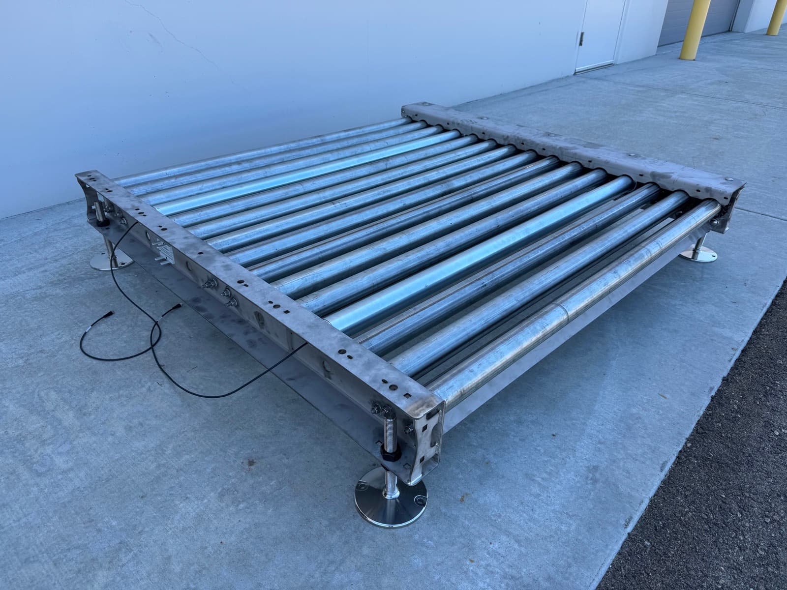 Stainless 24V MDR pallet conveyor section with leveling feet and a drive card cable
