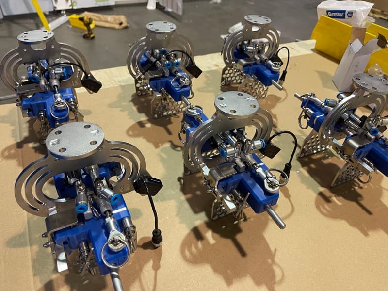 Custom robotic end effectors on assembly table showing precision stainless steel components